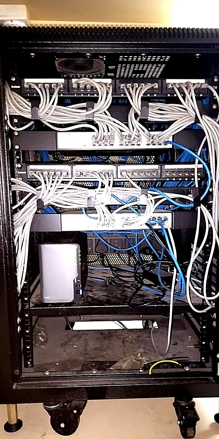 Before: long looping patch leads bundled across the front of a network rack, obscuring the panels behind them.